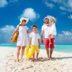 Keluarga menikmati liburan di pantai berpasir putih, salah satu dari 5 Destinasi Liburan Keluarga di Indonesia yang Wajib Dikunjungi Tahun Ini.