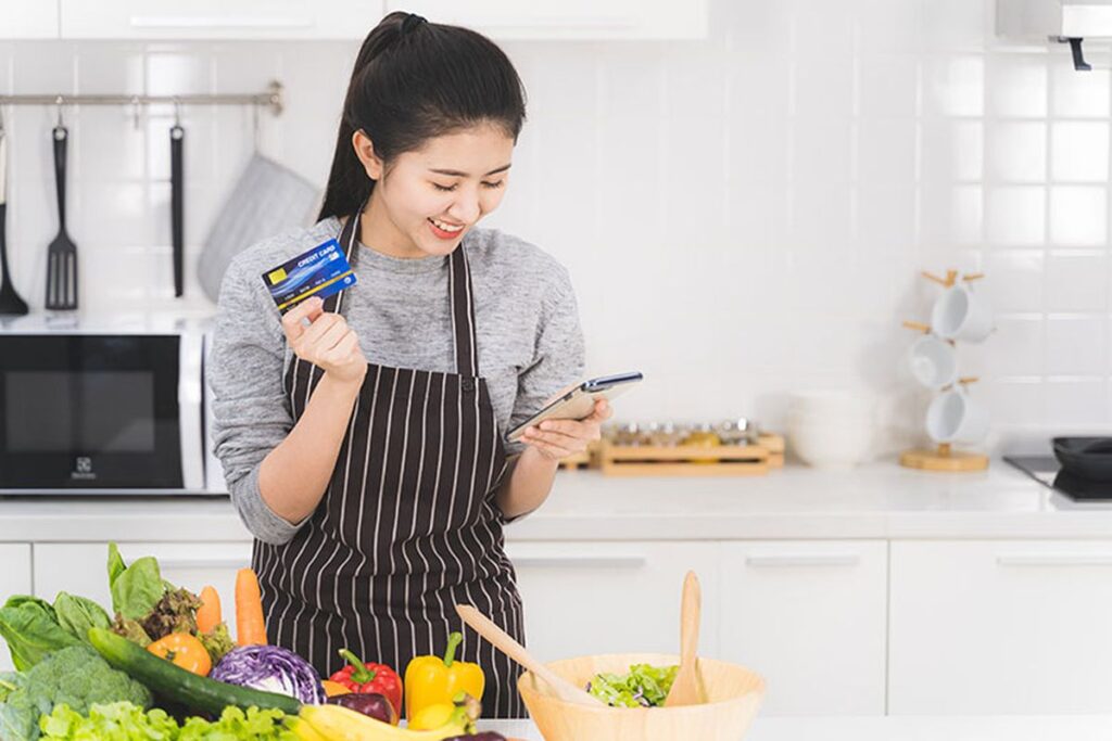 Wanita sedang berbelanja online sambil mencatat pengeluaran, menggambarkan tips belanja hemat di marketplace.