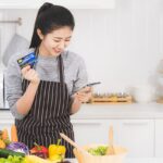 Wanita sedang berbelanja online sambil mencatat pengeluaran, menggambarkan tips belanja hemat di marketplace.